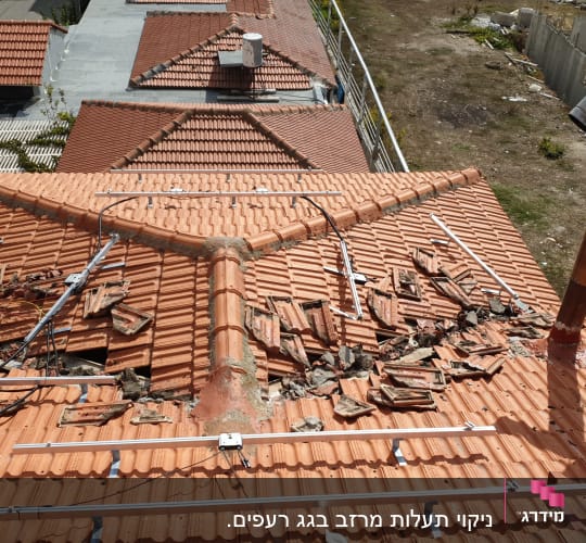 רעפים שבורים על גג רעפים עם צינור מתכת